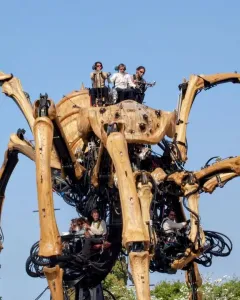 La Princesse, a giant mechanical spider with segmented legs and people operating it beneath a blue sky.