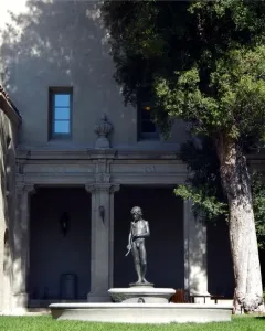 Spirit of Spanish Music, a bronze boy statue holding a long pipe-like instrument in a courtyard fountain.