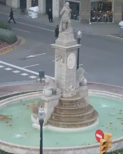 The Fountain of Hercules in a circular pool, with a stone figure on a tiered pedestal flanked by lion sculptures.