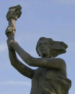 Victims of Communism Memorial statue of a female figure holding a torch aloft against a blue sky.