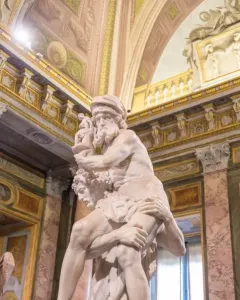 A marble sculpture of Aeneas, Anchises and Ascanius showing a man carrying an older man while a child clings to his leg.