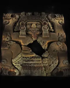 Tlaltecuhtli Monolith with a fanged mouth, elaborate headdress, and clawed limbs in reddish-brown stone.