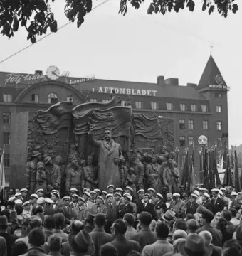 The Branting Monument shows a bronze figure addressing a crowd of workers with banners, with people gathered in front and the Aftonbladet building behind.
