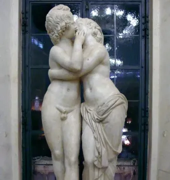 Cupid and Psyche marble sculpture showing two youthful figures embracing and kissing.