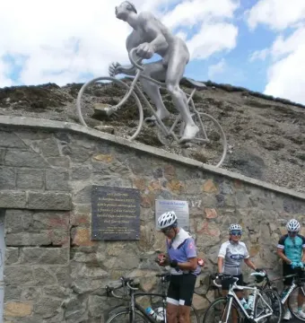 Géant du Tourmalet sculpture of a nude cyclist on a bicycle with three real cyclists standing below.