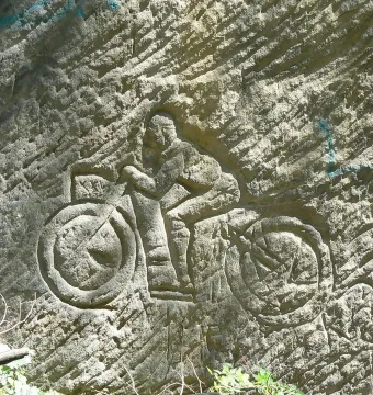 Klácelka sandstone relief of a motorcyclist riding left on a stone wall