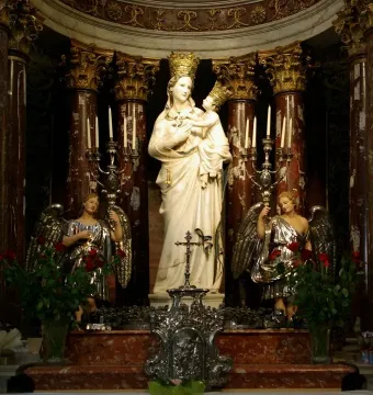 Madonna di Trapani statue of the Madonna and Child with gold crowns on an ornate altar, flanked by angels and red roses.