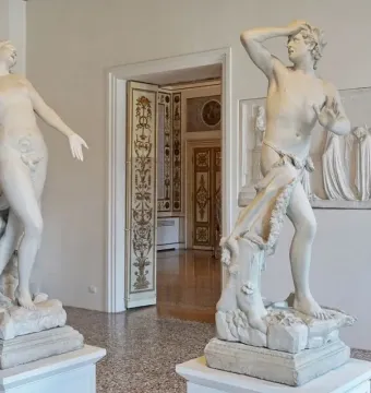 Orfeo y Eurídice marble statues facing each other in a museum room, with Eurydice reaching out and Orpheus holding a hand to his brow.