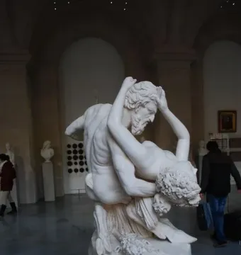 Satyre et bacchante marble sculpture of a bearded male figure holding a female in a museum gallery