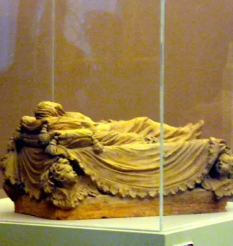 A bozzetto of the Veiled Christ showing a recumbent figure draped in finely folded fabric inside a glass display case.