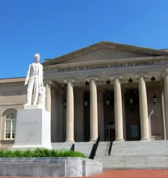 Abraham Lincoln marble statue on a stone pedestal in front of a classical courthouse building