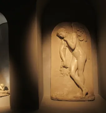 Marble bas-relief in the Monument to Elena Pavlovna, showing a winged male figure holding a garland and staff in an arched niche.