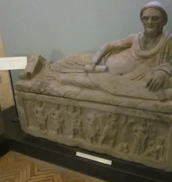 Sarcophagus of Laris Pulenas with a reclining male figure on the lid and carved relief figures along the base.