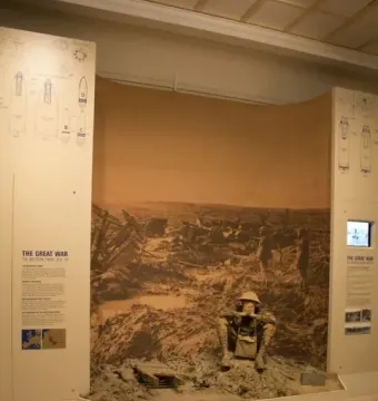 Man in the mud diorama showing a seated soldier in helmet surrounded by mud and debris, with a wartime backdrop and information panels.