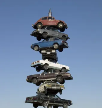 Spindle sculpture in Berwyn, Illinois, with eight cars stacked on a vertical spike against a clear blue sky.