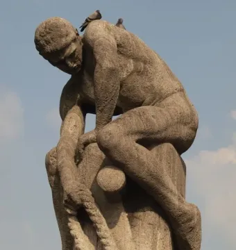 Tauzieher stone sculpture of a muscular man pulling a thick rope beside a stone bollard, with two pigeons on his back.