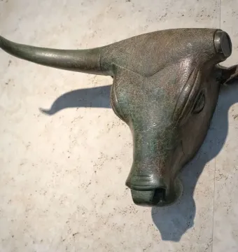 Toros de Costitx bronze bull head mounted on a textured stone wall.
