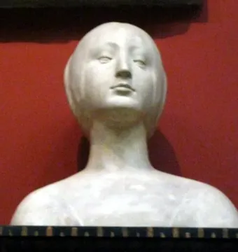 White marble bust of a princess with stylized features and pulled-back hair on a dark base.