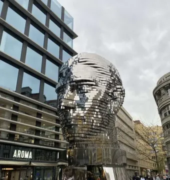 The Head of Franz Kafka sculpture in Prague, a towering reflective metal head made of layered panels.