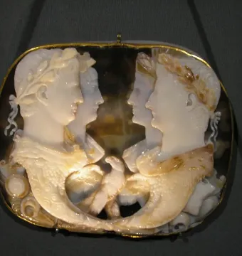 Gemma Claudia oval onyx cameo with four profile figures in relief and a gold border.