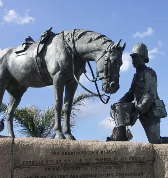 Horse Memorial sculpture showing a saddled horse beside a kneeling uniformed figure holding out a pail.