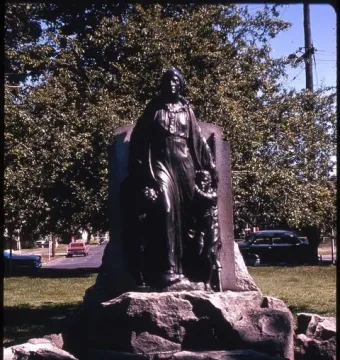 Pioneer Mother Memorial bronze statue of a woman on a stone base, flanked by smaller figures and surrounded by trees.