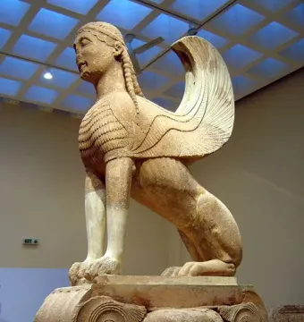 Sphinx of Naxos stone sculpture with a woman\'s head, lion\'s body, and carved wings on an ornate volute base.