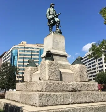 Admiral David G. Farragut statue atop a tall stone pedestal with naval decorations in a park setting.