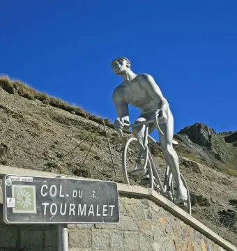 Géant du Tourmalet sculpture of a cyclist climbing against rugged mountain peaks.