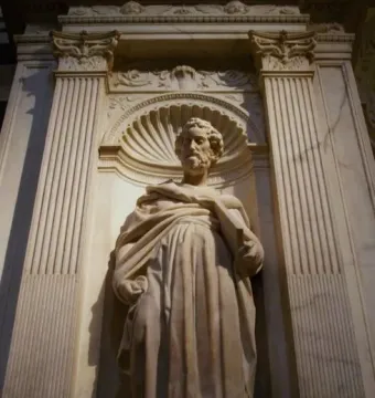 Saint Peter marble statue in an ornate niche, holding a book and wearing flowing robes.