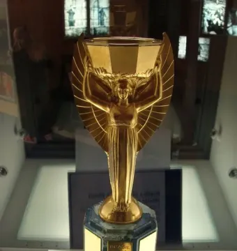 Jules Rimet Trophy replica with a winged female figure holding a cup aloft on a dark octagonal base.