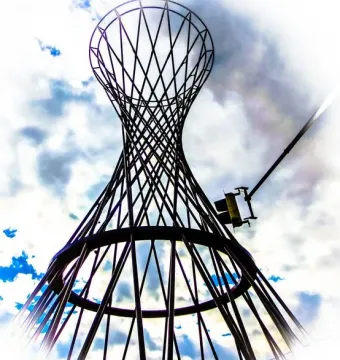Mae West sculpture silhouetted against a bright cloudy sky with blue patches.