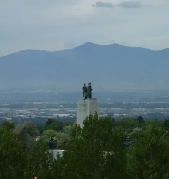 This Is the Place Monument framed by trees with Salt Lake Valley and distant mountains beyond.