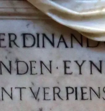 Close-up of the Tomb of Ferdinand van den Eynde showing engraved marble inscription and part of a draped sculptural element.