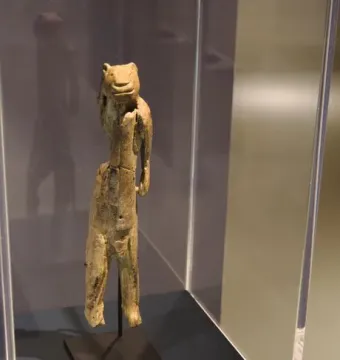 Lion-man figurine displayed in a glass case on a slender dark mount.