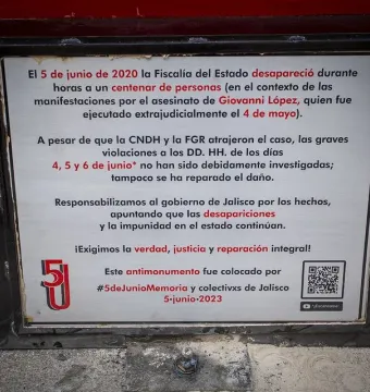 Close-up of the Antimonumento 5J metal plaque with Spanish text and a QR code.