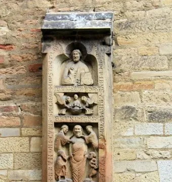 Weathered stone relief of the Tomb of Bruno the Priest, showing stacked figural scenes and vertical inscriptions on a wall.