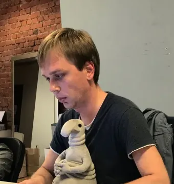 Homunculus Loxodontus sculpture seated on a desk beside a person working on a laptop.