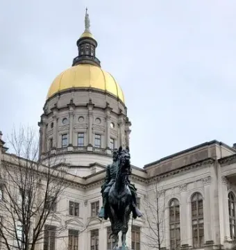 John Brown Gordon equestrian statue on a tall stone pedestal in front of a domed capitol building.