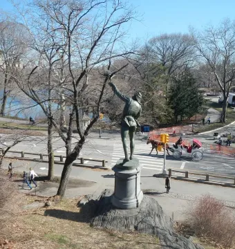 The Falconer bronze statue seen from behind, standing on a stone pedestal with one arm raised.