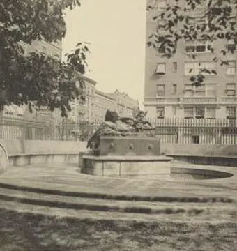 The Great God Pan fountain with a dark sculpture on a stone base in an urban park setting.