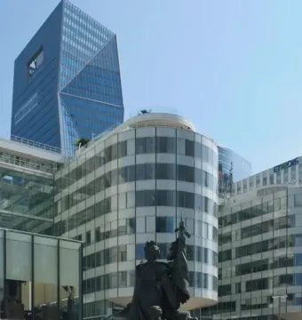 La Défense de Paris bronze memorial statue with a central female figure holding a standard, standing before modern glass skyscrapers.
