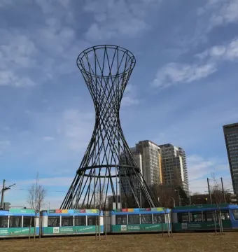 Mae West sculpture with a tram passing in front of it under a partly cloudy sky.