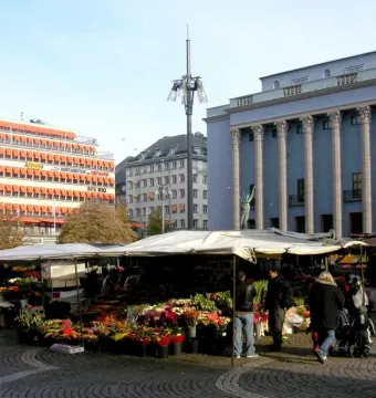 The Orpheus Fountain bronze statue is partially visible above market stalls in Stockholm.