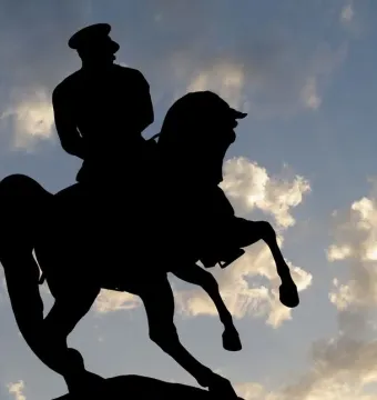 Silhouette of the Statue of Honor equestrian monument against a cloudy sky.