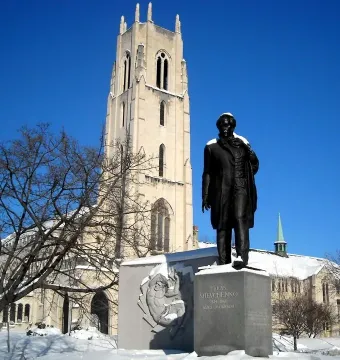 Taras Shevchenko Memorial statue on a snow-dusted pedestal with a church tower behind it.