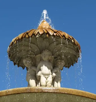 Fountain of the Artichoke with three cherubs supporting a leaf-covered stone canopy as water cascades over the edge.