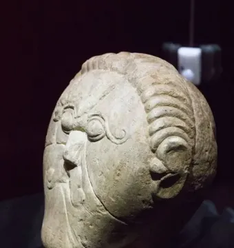 Mšecké Žehrovice Head stone sculpture with stylized eyes, ridged hair, and a torque around the neck.
