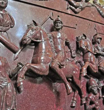 Relief carving on the Sarcophagus of Helena showing soldiers on horseback, standing figures, a bust, and winged figures with a garland.