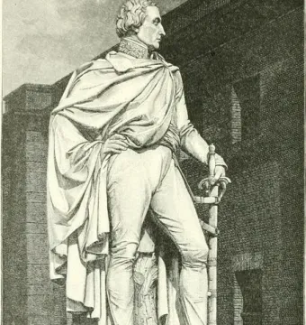 Bülow Monument showing a full-length statue of a Prussian general in a cloak standing on a pedestal with a sword at his side.